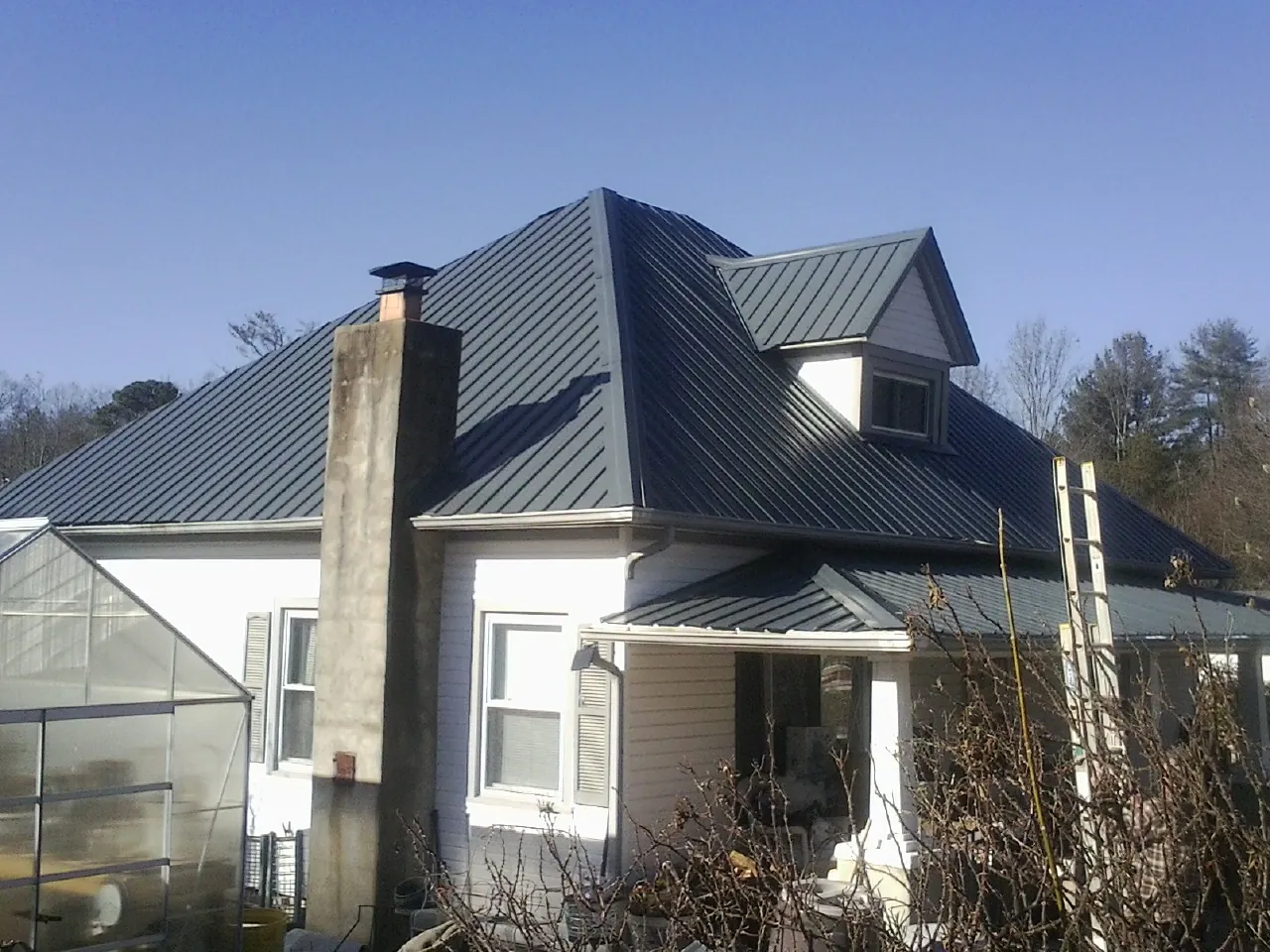 Dark blue standing seam metal roof on a white farmhouse with dormer — Slate & Tile Roof Repair by Roofing Brothers in Drifton