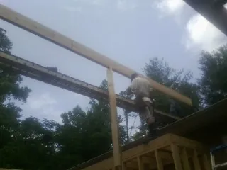 Carpenter setting a ridge beam over a new addition frame — Ice Dam Removal by Roofing Brothers in Drifton