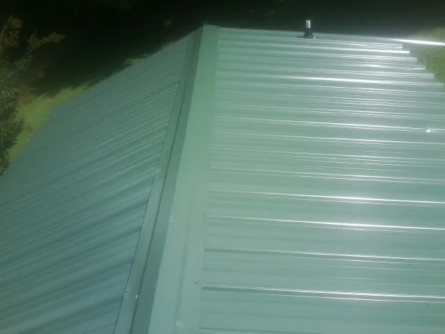 New green metal panels meeting at the ridge of a roof — Flat Roof Repair work by our crew in Drifton