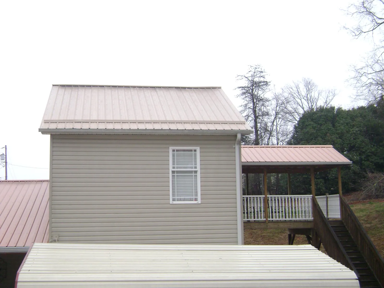 Tan metal roofs on a two story addition and attached porch, from a Roof Replacement job in Drifton