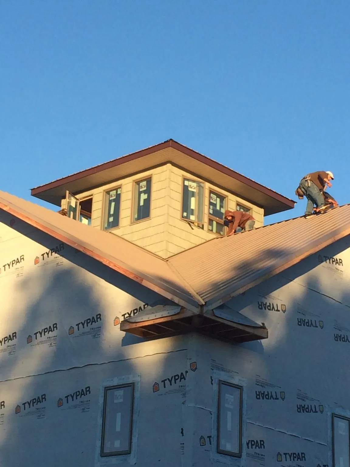 Roofers working around a rooftop cupola on a new metal roof at sunset — Roof Waterproofing in Drifton by Roofing Brothers